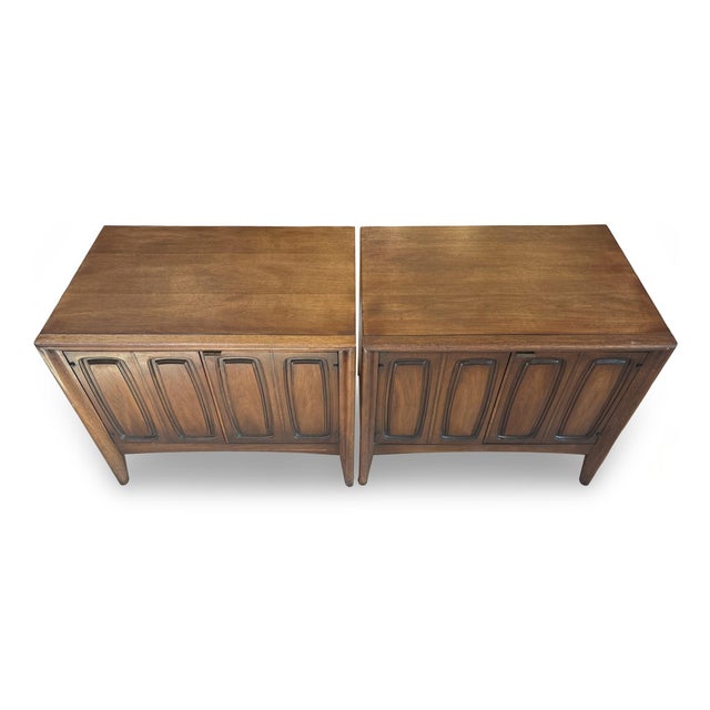 Pair of mid-century modern Kent Coffey walnut Perspecta nightstands. The nightstands open for storage, and feature the...