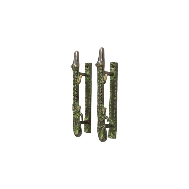 A pair of green brass alligator door handles or cabinet pulls. Pressed with simple details to convey skin, eyes and toes....