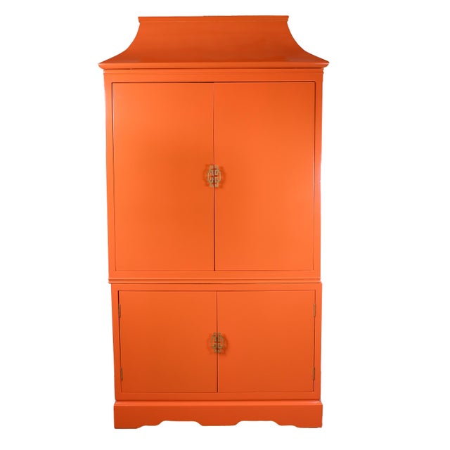 Bold and beautifully styled, this Chinoiserie armoire features a dramatic pagoda top and a vibrant orange lacquered...
