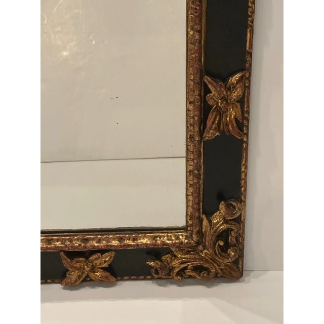Dramatic ebonized and gilded super chunky heavily carved mirror having a stylized fleur de lis motif. Mirror 17 w 24 h