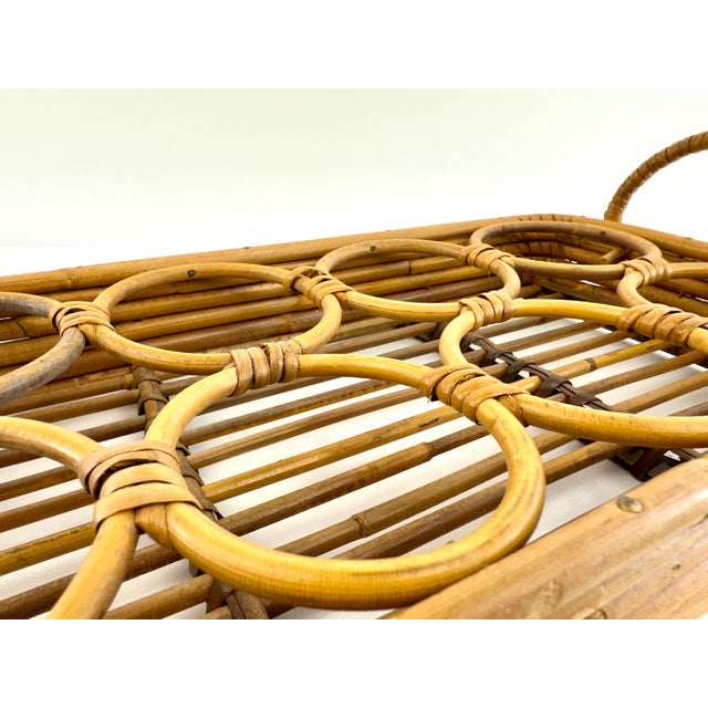Mid-century rattan drink caddy featuring an integrated circular bottle rack with wrapped handles and warm honey-toned cane...