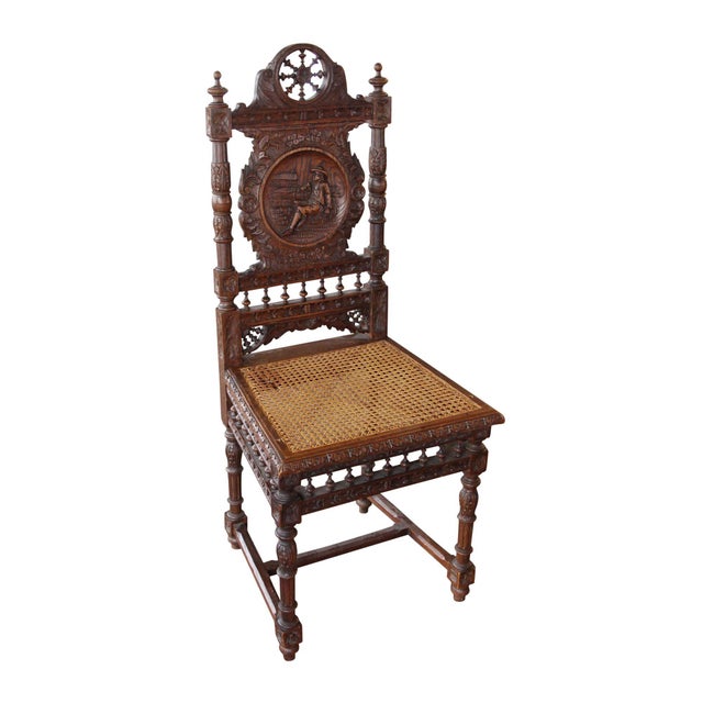 Dark wood tone carved English Renaissance style chairs with a wicker seat. Each chair back has a different carved figural...