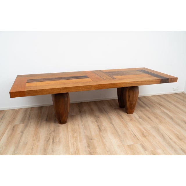 Bagutta dining table by Henk Vos. The tabletop is inlaid with various types of wood on large solid wooden legs. This piece...