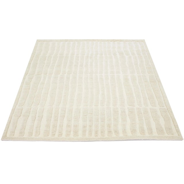 This Moroccan-style wool rug is hand-knotted and showcases a beautiful modern design with a natural ivory field. It...