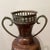 Discover the timeless elegance of this Vintage Middle Eastern Copper and Brass Amphora Vase, featuring distinctive handles...