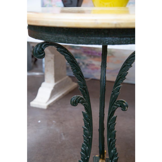 This is an attractive French green-painted and parcel gilt circular iron table. The Faux Travertine top is supported by...