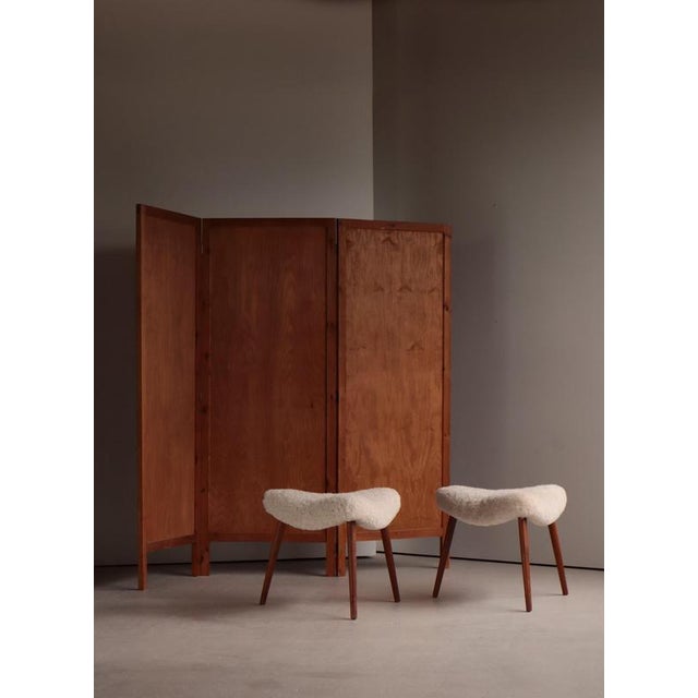 Elegant pair of Scandinavian Modern stools dating to the 1950s Denmark, featuring sculptural tripod legs in richly grained...