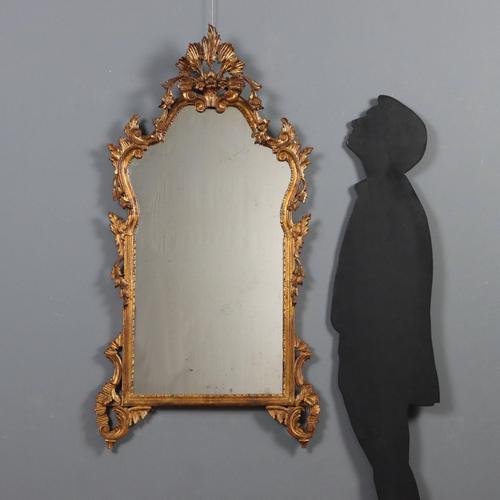 Carved and gilded late Baroque mirror. The frame is richly carved with scrolls and curls, floral and leafy arrangements....