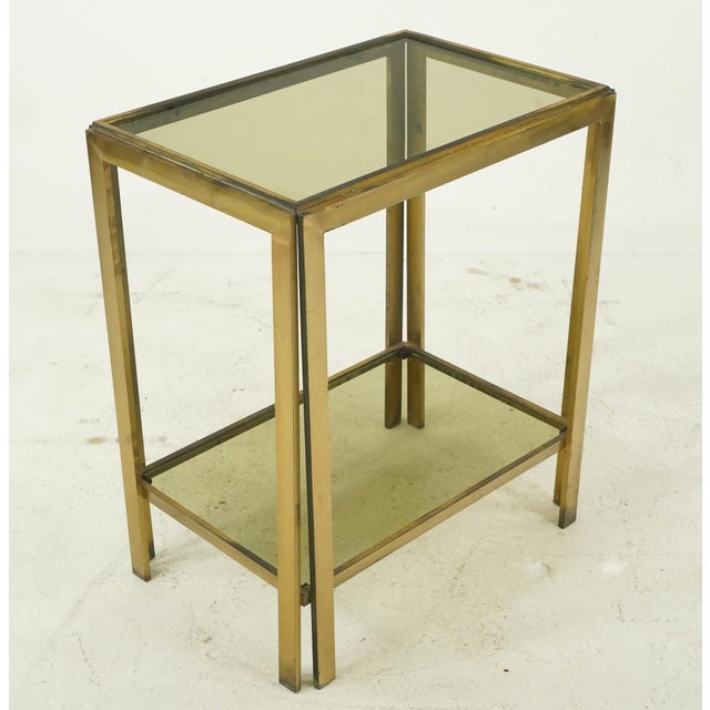 Mid Century Italian made side tables made of a brass frame and smoky glass shelves. Good condition with surface wear and...