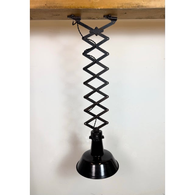 This vintage Industrial adjustable scissor ceiling lamp was produced in former Czechoslovakia during the 1930s. It...