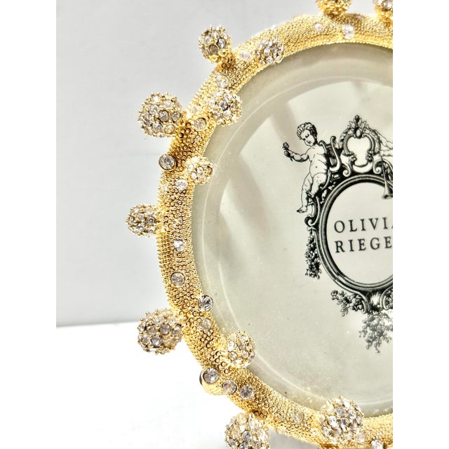 A glamorous 1990s Olivia Riegel picture frame featuring gilt metal construction adorned with sparkling crystal accents....