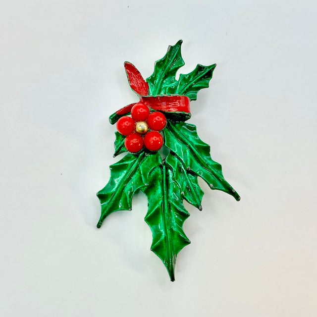 A lovely Christmas Brooch from the Mid 20th Century. It features a bright green painted swag of holly leaves with red...