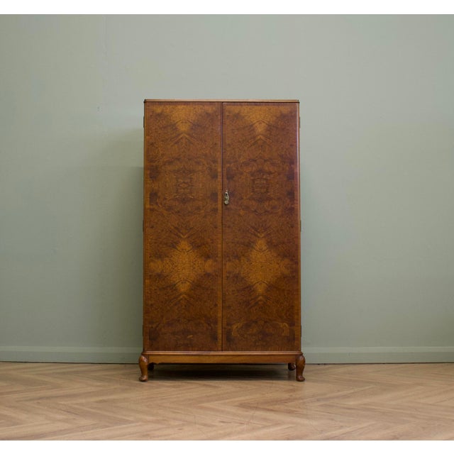 A superb quality compact wardrobe dating from the 1930s, featuring beautifully figured burr walnut doors with contrasting...
