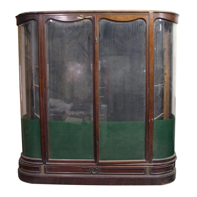 English walnut wood showcase with a bowfront silhouette. Elegant curved lines and beveled edges on the glass panes...