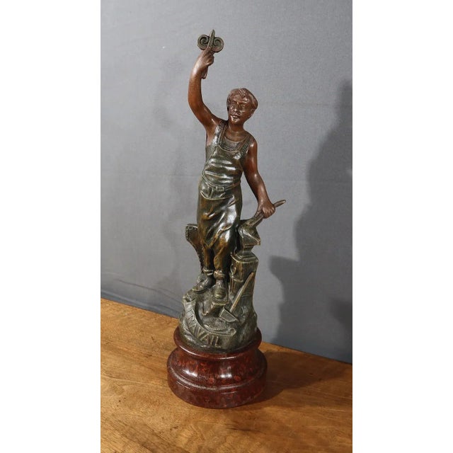 Regula subject with green and brown patina, depicting an active blacksmith, dressed in his working clothes and surrounded...