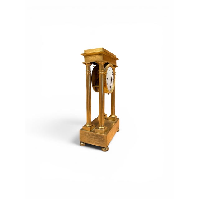 An elegant miniature French Empire-period portico clock crafted in bronze doré. The architectural case features four...
