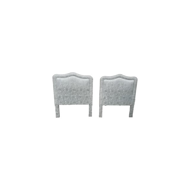 The headboards are upholstered in a richly textured woven jacquard featuring an intricate tonal pattern in muted blue-...