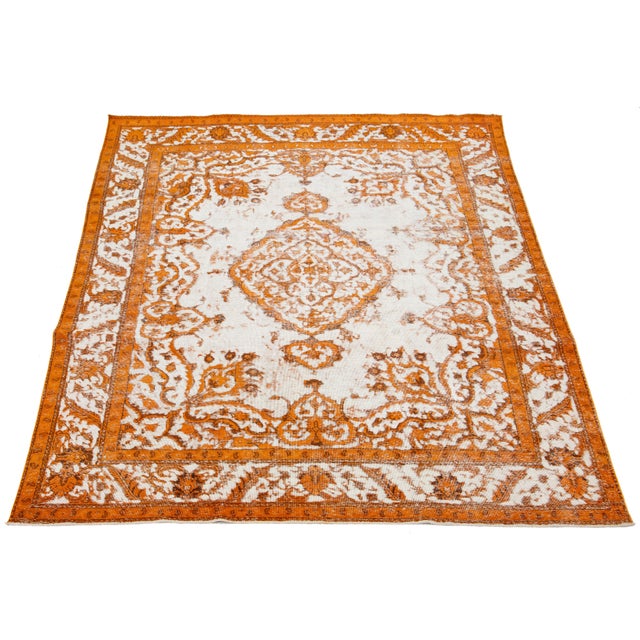 This is a Persian wool rug with an ivory base color, a medallion floral design, and orange accents. It is hand-knotted and...