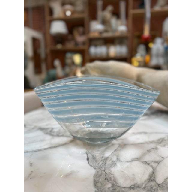 Elegant Murano glass bowl featuring a graceful asymmetric form and delicate translucent blue and clear striped pattern....