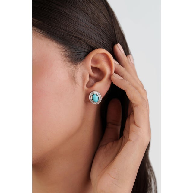 These Halo Stud Earrings showcase 2.52 carats of oval turquoise cabochons, set in 14k white gold. Each turquoise measuring...