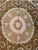 Hand-embroidered Suzani panel from Uzbekistan — a tan starburst medallion with a pink rosette centre on an ivory ground,...
