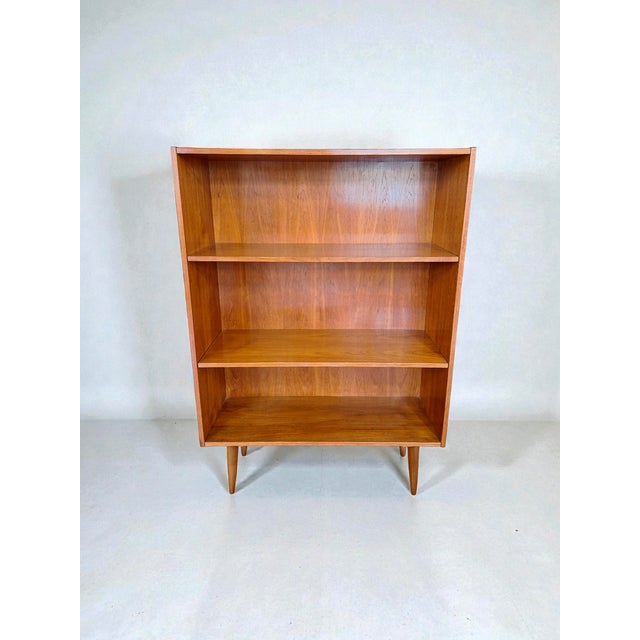 Freestanding bookcase with two height-adjustable shelves, made of teak in Denmark in the 1960s. The shelves can be...