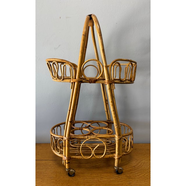 This mid-20th century Italian rattan bar cart is a charming blend of craftsmanship and bohemian spirit. Its bent bamboo...