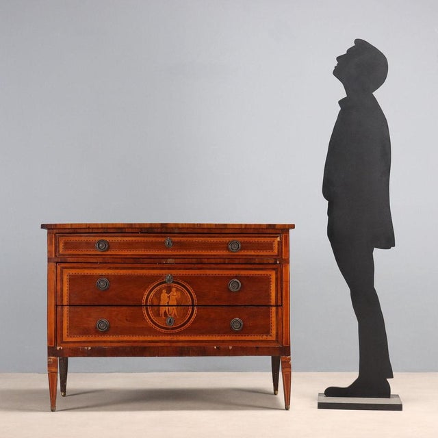 Neoclassical walnut chest of drawers with cherry, maple, and walnut trim. Inlaid rosette with a musician in the center of...