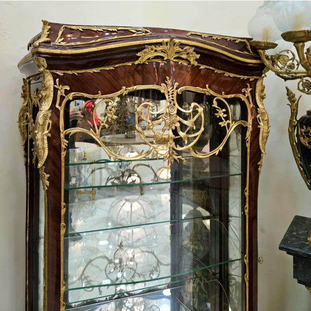 Showcase your most treasured collectibles in this magnificent French Louis XV Curio Display Cabinet, a luxurious statement...