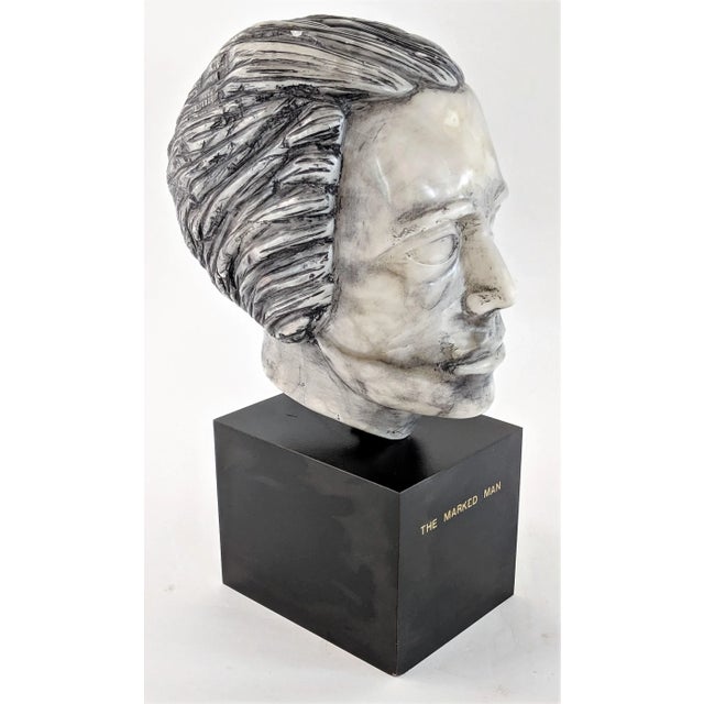 Strange marble male bust on wood base titled "The Marked Man". Measures 16" tall.