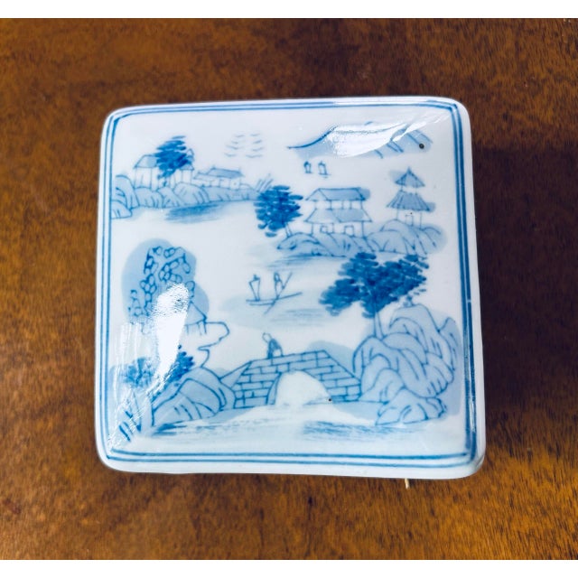 Chinoiserie 4" square porcelain lidded box. Hand-painted "Sansui" (mountain and water) landscape. The scene features a...