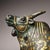 The bull stands in a commanding pose with its head slightly raised. The surface is richly decorated with archaic-style...