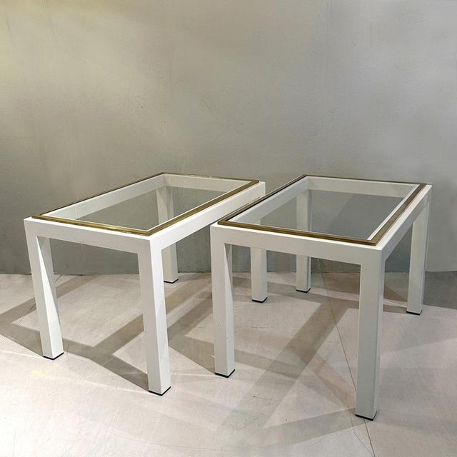 Pair of rectangular coffee tables circa 1970. The angular metal frame is coated in cream with top edge in brass framing...