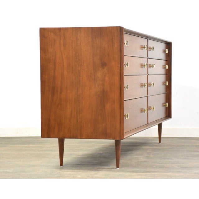An exquisite mid century modern walnut eight drawer dresser designed by Paul Frankl for Johnson Furniture with polished...