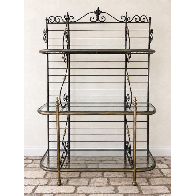 An elegant vintage French-style baker’s rack featuring a wrought iron frame accented with brass and 9 glass shelves....