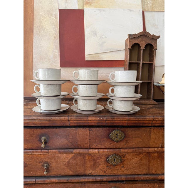 A beautifully cohesive set of nine Zaalberg Holland cup and saucer duos, finished in a soft, speckled glaze with subtle...