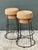A pair of vintage bar stools featuring cork and metal construction, likely from the mid-20th century. The stools present a...
