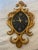 Striking vintage Welby wall clock featuring an ornate giltwood frame with sweeping scrollwork and floral rosette details....