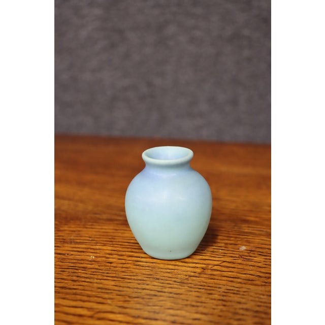 Antique Van Briggle Pottery vase in a soft matte blue glaze, featuring a simple rounded body with a narrow neck and gently...