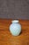 Antique Van Briggle Pottery vase in a soft matte blue glaze, featuring a simple rounded body with a narrow neck and gently...