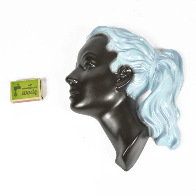 A ceramic wall figure depicting a portrait of a woman in profile. Model 3408 mask produced in the 1950s in Germany by...