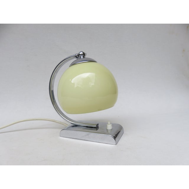 A bedside lamp crafted in the strict design language of the Bauhaus era, made of chrome-plated brass. The base is...