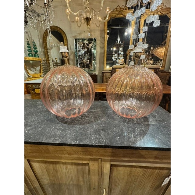 The product is a pair of large scale pink Murano globe lamps. These elegant and vibrant lamps are perfect for adding a...