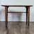 This vintage mid-century modern end table features a striking trapezoid-shaped top in bookmatched walnut veneer, sitting...