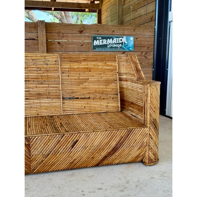 A bold and sculptural Mid-20th Century split rattan sofa, fully restored and showcasing exceptional craftsmanship. The...