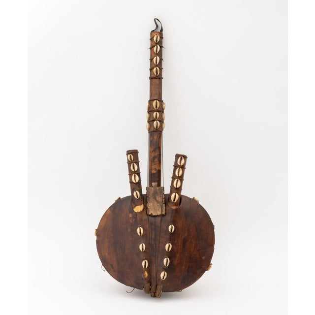 Two West African Musical Instruments, comprising: hide wrapped wood kora with gourd body and cowry shell accents and bow...