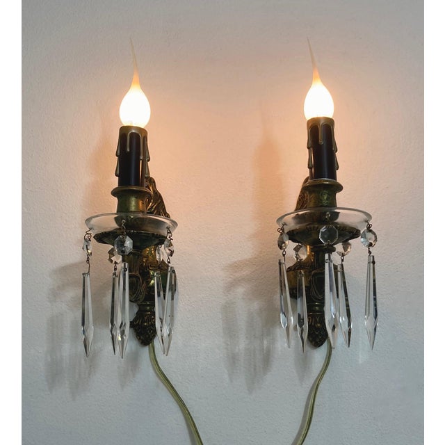 Petite bronze wall sconces with glass bobeches adorned with crystal drops. Black and gold drip candle covers. Torch top...