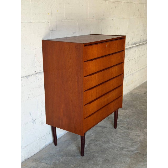 This tall dresser features six spacious drawers and clean architectural lines. Elevated on slender tapered legs, it offers...