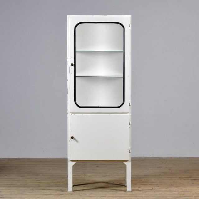 Vintage medicine cabinet from the 1970s, produced in Hungary. This cabinet is made of iron and glass, with the glass held...