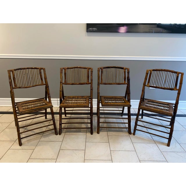 Set a four vintage scorched bamboo folding chairs with brass hinges. These vintage scorched bamboo folding chairs offer a...